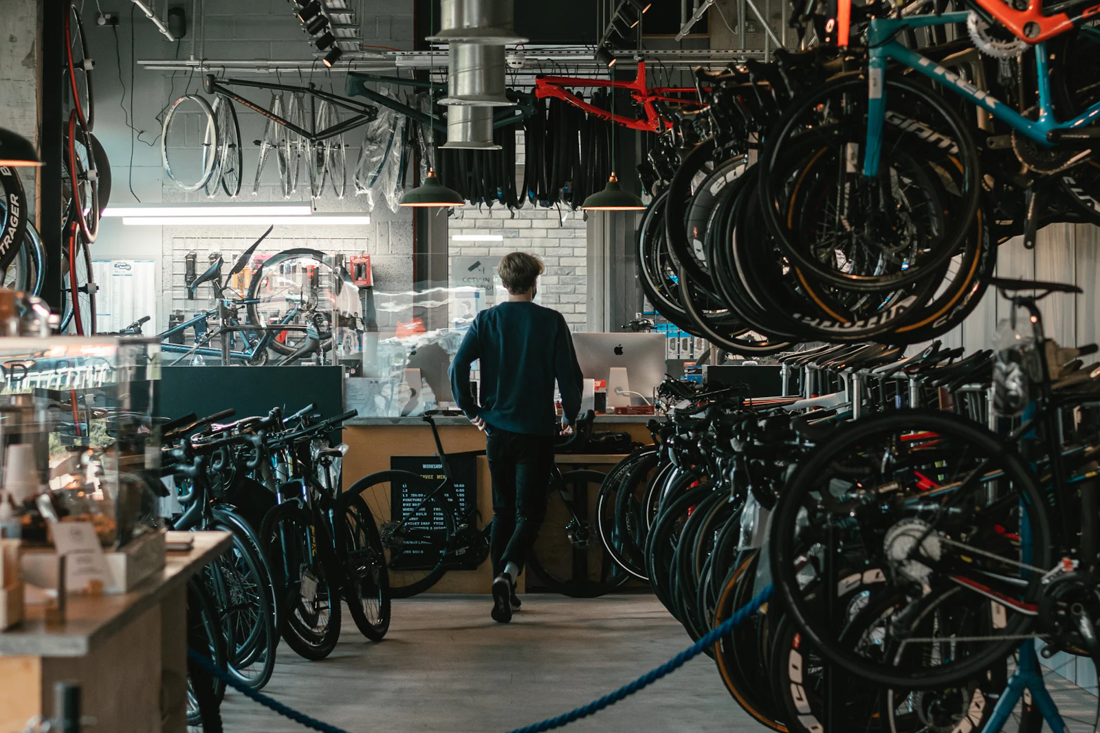 Comptoir d’un magasin de location de vélos équipé d’un ordinateur, entouré de vélos suspendus